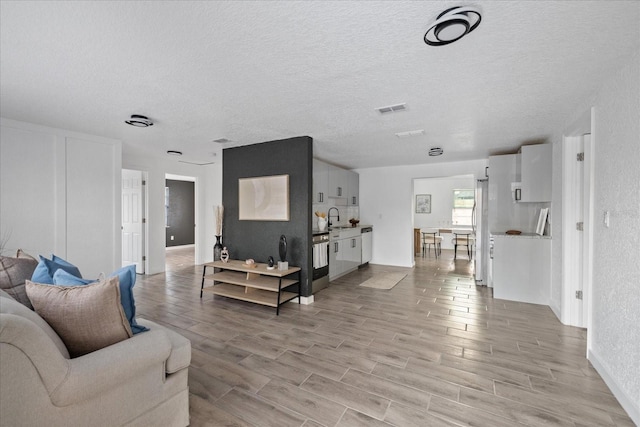 living room featuring wood tiled floor, visible vents, and a textured ceiling