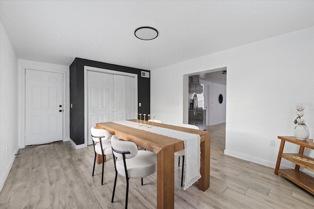 dining space featuring light wood-style floors and baseboards