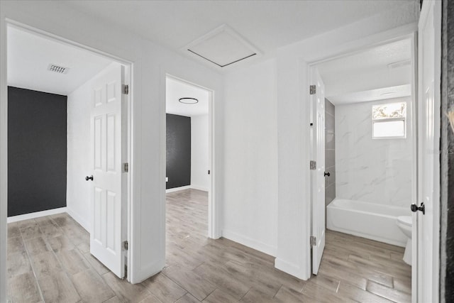 corridor featuring baseboards, wood finish floors, visible vents, and attic access