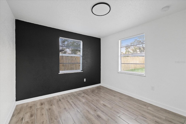 spare room with baseboards, wood finished floors, and a healthy amount of sunlight