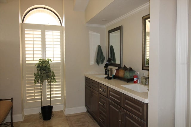 full bathroom with double vanity, ornamental molding, baseboards, and a sink