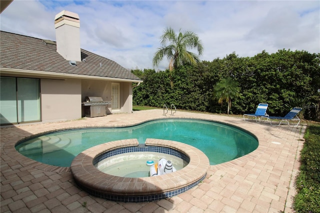 view of swimming pool featuring a grill, a pool with connected hot tub, and a patio