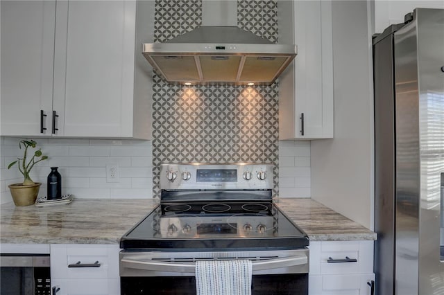 315 40th St S, Saint Petersburg, FL 33711 - kitchen featuring light stone counters, white cabinets, appliances with stainless steel finishes, decorative backsplash, and wall chimney exhaust hood