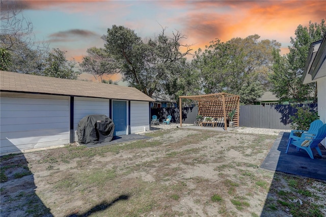 315 40th St S, Saint Petersburg, FL 33711 - yard at dusk with a garage, a fenced backyard, a pergola, and a patio