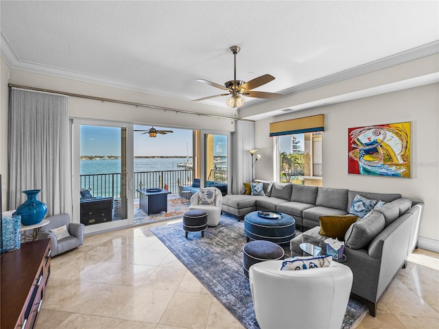 living area with a textured ceiling, ornamental molding, a water view, and a ceiling fan