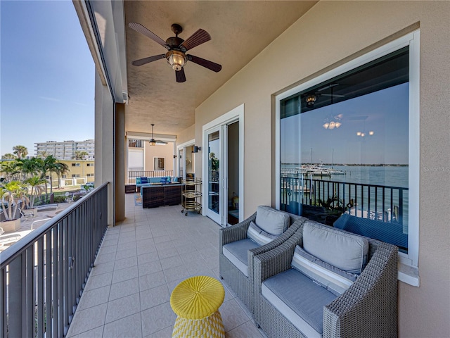 balcony featuring ceiling fan, a water view, and an outdoor living space