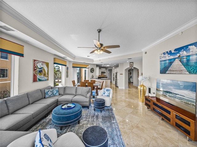 living area featuring arched walkways, crown molding, a textured ceiling, and ceiling fan