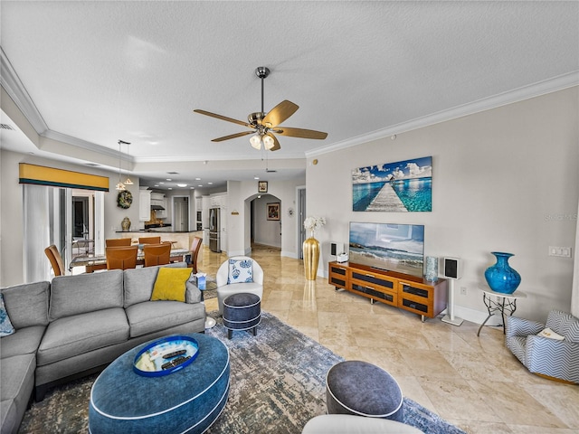 living room featuring baseboards, a textured ceiling, a ceiling fan, and crown molding