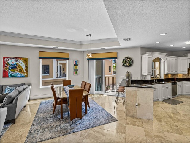 dining room with a textured ceiling, recessed lighting, visible vents, ornamental molding, and a tray ceiling