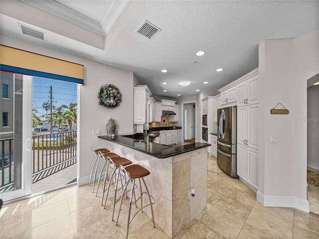 kitchen with stainless steel appliances, a breakfast bar, visible vents, and a peninsula