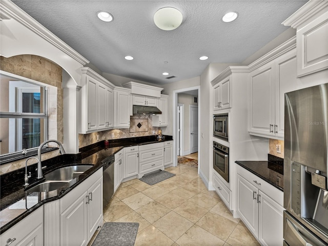 kitchen featuring appliances with stainless steel finishes, white cabinetry, a sink, and tasteful backsplash