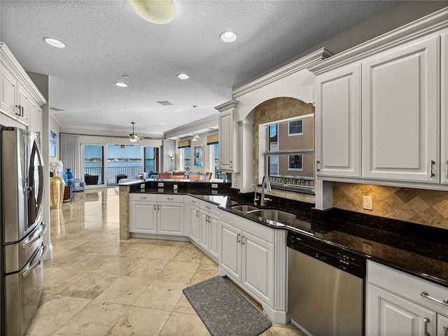 kitchen with a fireplace, appliances with stainless steel finishes, open floor plan, a sink, and a peninsula