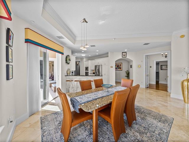 dining area with baseboards, visible vents, arched walkways, a tray ceiling, and crown molding