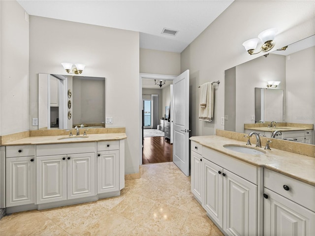 bathroom featuring visible vents, two vanities, and a sink