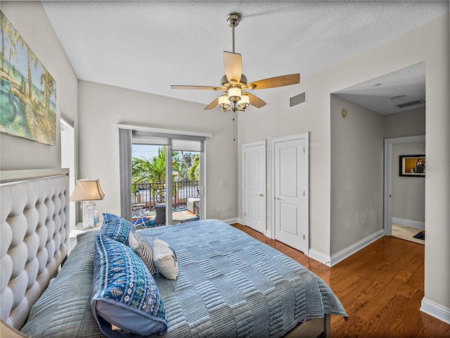 bedroom with access to exterior, visible vents, baseboards, and wood finished floors