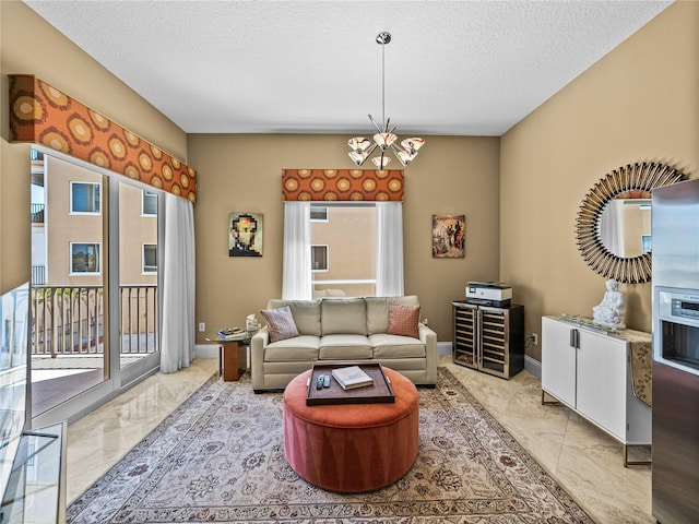 living area with a chandelier, marble finish floor, a textured ceiling, and baseboards