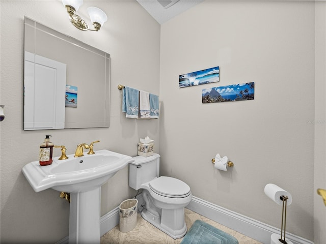 half bath featuring tile patterned flooring, a sink, toilet, and baseboards