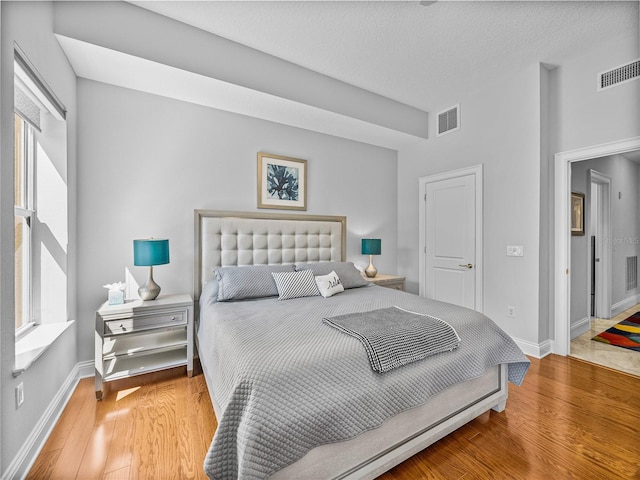 bedroom featuring baseboards, visible vents, and wood finished floors