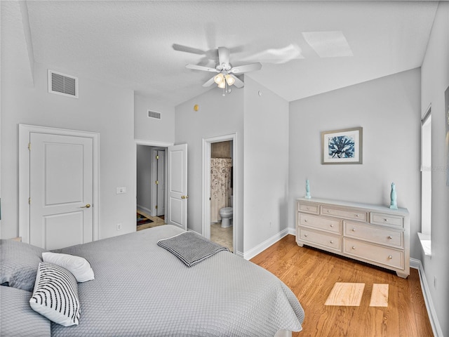 bedroom featuring light wood-type flooring, baseboards, visible vents, and vaulted ceiling