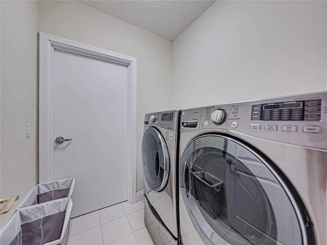 laundry room with laundry area, a textured ceiling, washing machine and clothes dryer, and light tile patterned floors