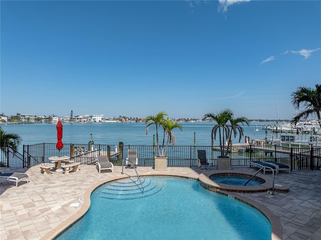 community pool featuring a water view, a patio area, fence, and a hot tub