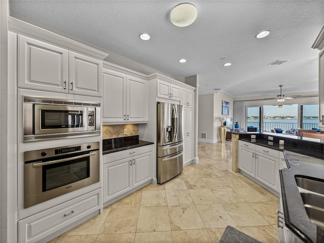 240 108th Ave Unit 102, Treasure Island, FL 33706 - kitchen featuring appliances with stainless steel finishes, white cabinetry, dark countertops, a textured ceiling, and recessed lighting
