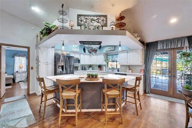 kitchen featuring light wood-style flooring, a center island, stainless steel appliances, light countertops, and white cabinetry