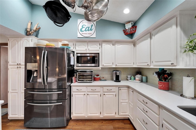 kitchen with stainless steel appliances, white cabinets, light countertops, and wood finished floors