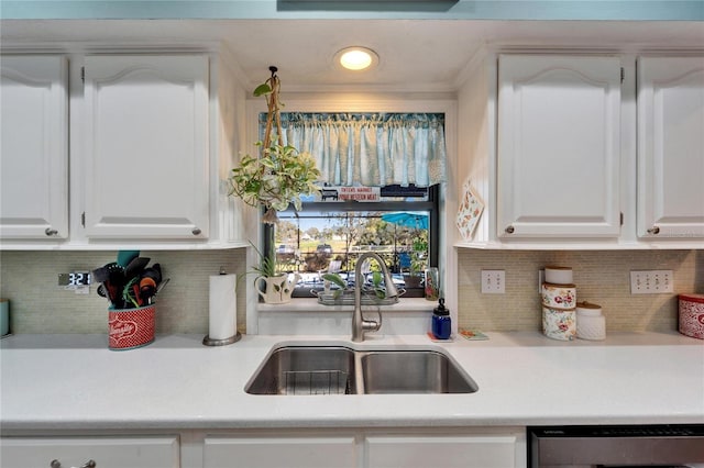 kitchen featuring light countertops, stainless steel dishwasher, a sink, and white cabinetry