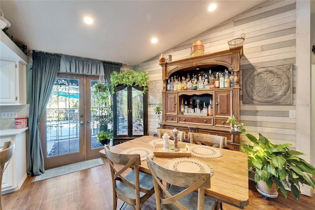 bar featuring recessed lighting, wooden walls, light wood-style floors, vaulted ceiling, and french doors