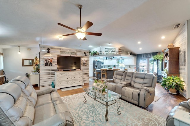 living area featuring lofted ceiling, ceiling fan, light wood finished floors, and visible vents