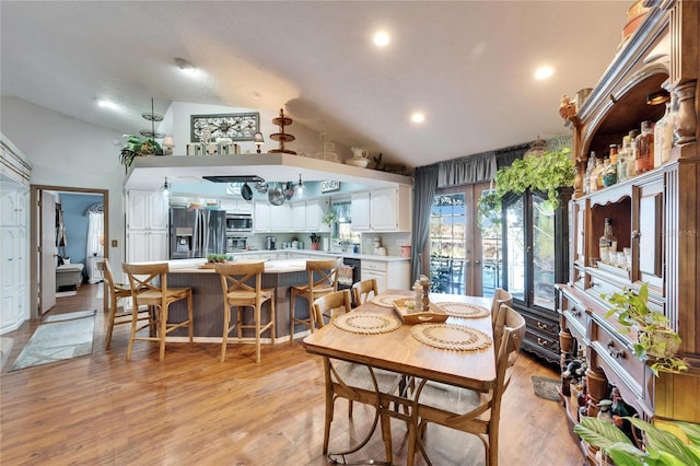 dining area with light wood-style floors, french doors, and vaulted ceiling