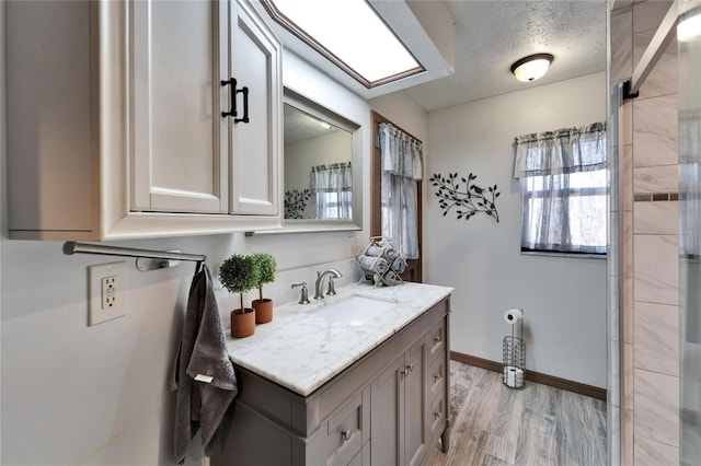 bathroom with vanity, baseboards, a textured ceiling, and wood finished floors