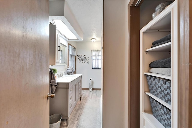 bathroom featuring baseboards, wood finished floors, and vanity