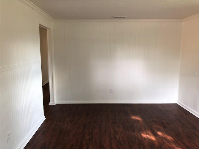 spare room with dark wood-style floors, baseboards, visible vents, and ornamental molding