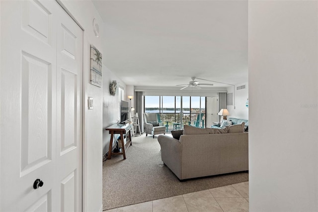 living room with light tile patterned floors, visible vents, light colored carpet, and ceiling fan