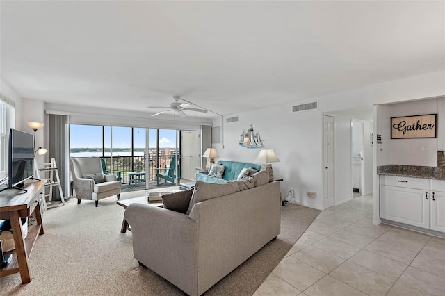 living room featuring light tile patterned floors, baseboards, visible vents, and ceiling fan