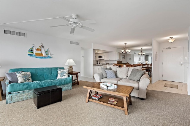 living room with visible vents, light carpet, light tile patterned flooring, and ceiling fan with notable chandelier