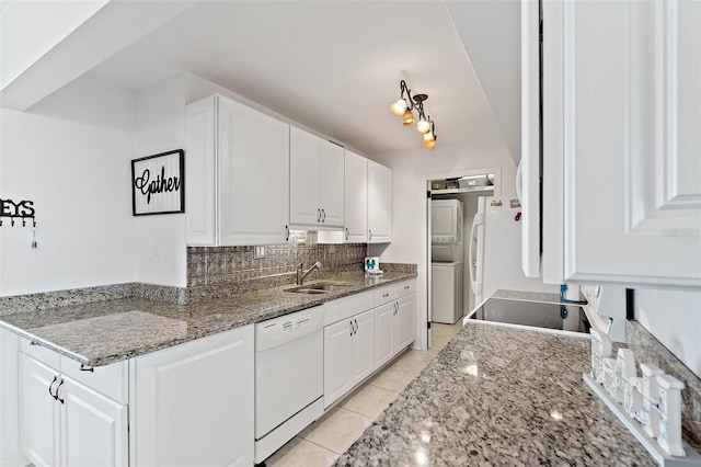 kitchen featuring decorative backsplash, a sink, white cabinetry, white dishwasher, and stacked washer / drying machine