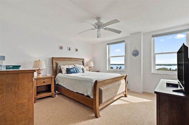 bedroom with ceiling fan, multiple windows, baseboards, and light carpet