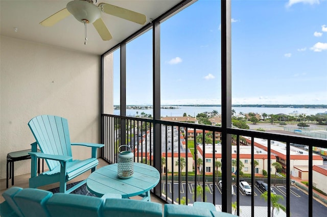 sunroom with ceiling fan and a water view