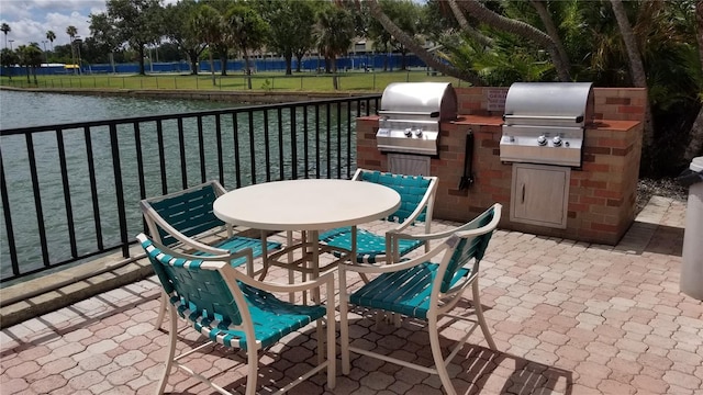 view of patio featuring grilling area, outdoor dining space, exterior kitchen, and a water view