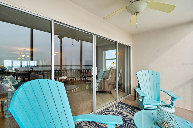 sunroom featuring ceiling fan with notable chandelier