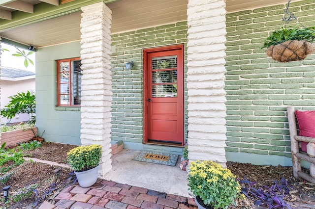 entrance to property with a porch and brick siding