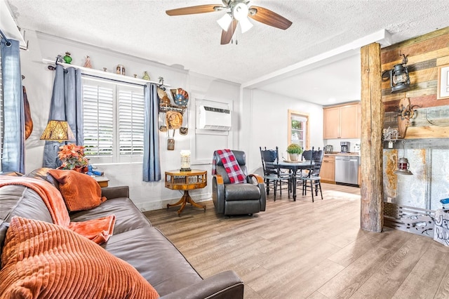 living area featuring light wood-style flooring, a textured ceiling, a ceiling fan, and an AC wall unit