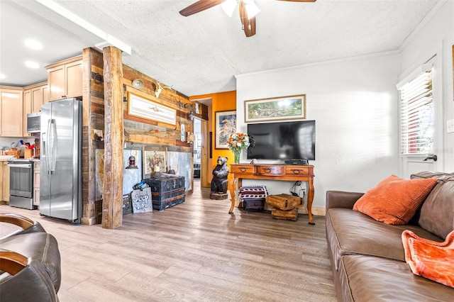 living area with a textured ceiling, ceiling fan, light wood finished floors, and ornamental molding