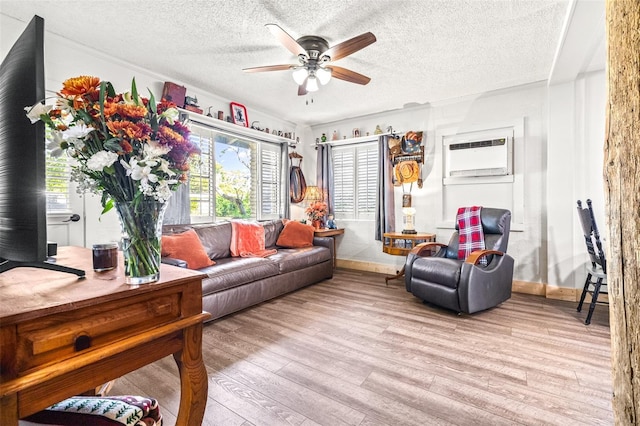 living room featuring a textured ceiling, an AC wall unit, wood finished floors, and a ceiling fan