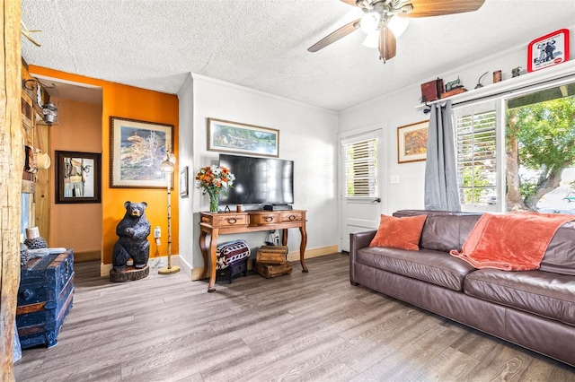 living area featuring a textured ceiling, ceiling fan, wood finished floors, and baseboards