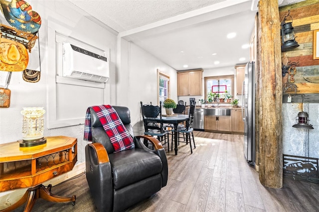 interior space with light wood-type flooring, a wall unit AC, a textured ceiling, and recessed lighting