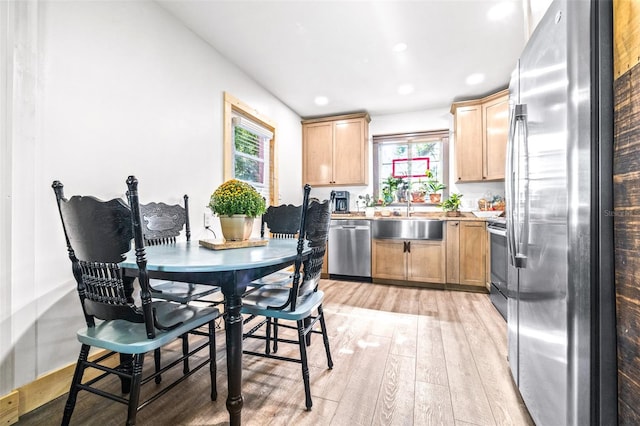 kitchen featuring stainless steel appliances, light wood-style floors, light brown cabinets, a sink, and plenty of natural light